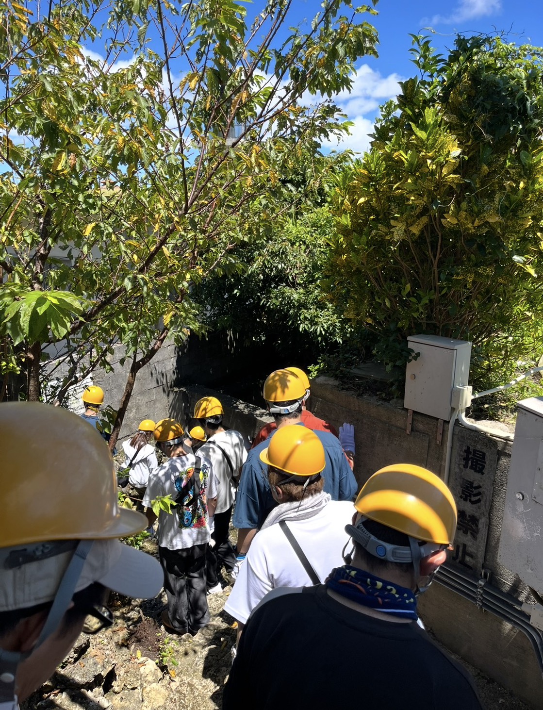 ヘルメットを被ってアブチラガマの入口へ向かう見学者たち
